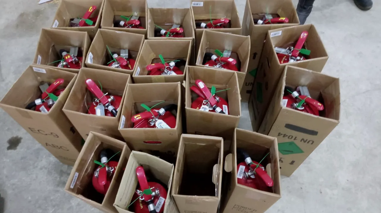 Boxed fire extinguishers laid out on a floor before delivery