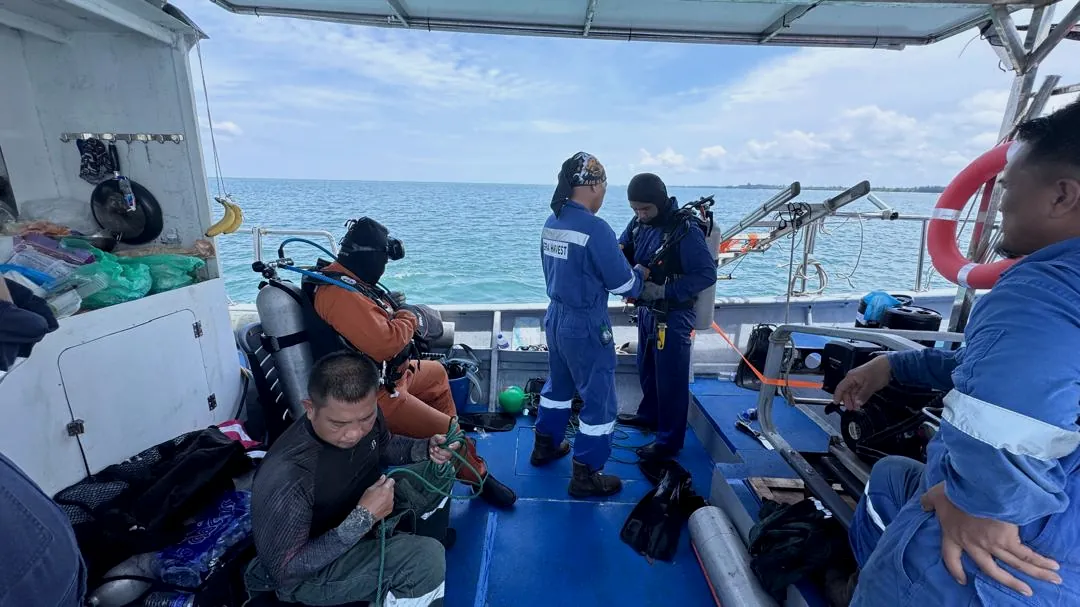 Divers preparing equipment on a workboat at sea